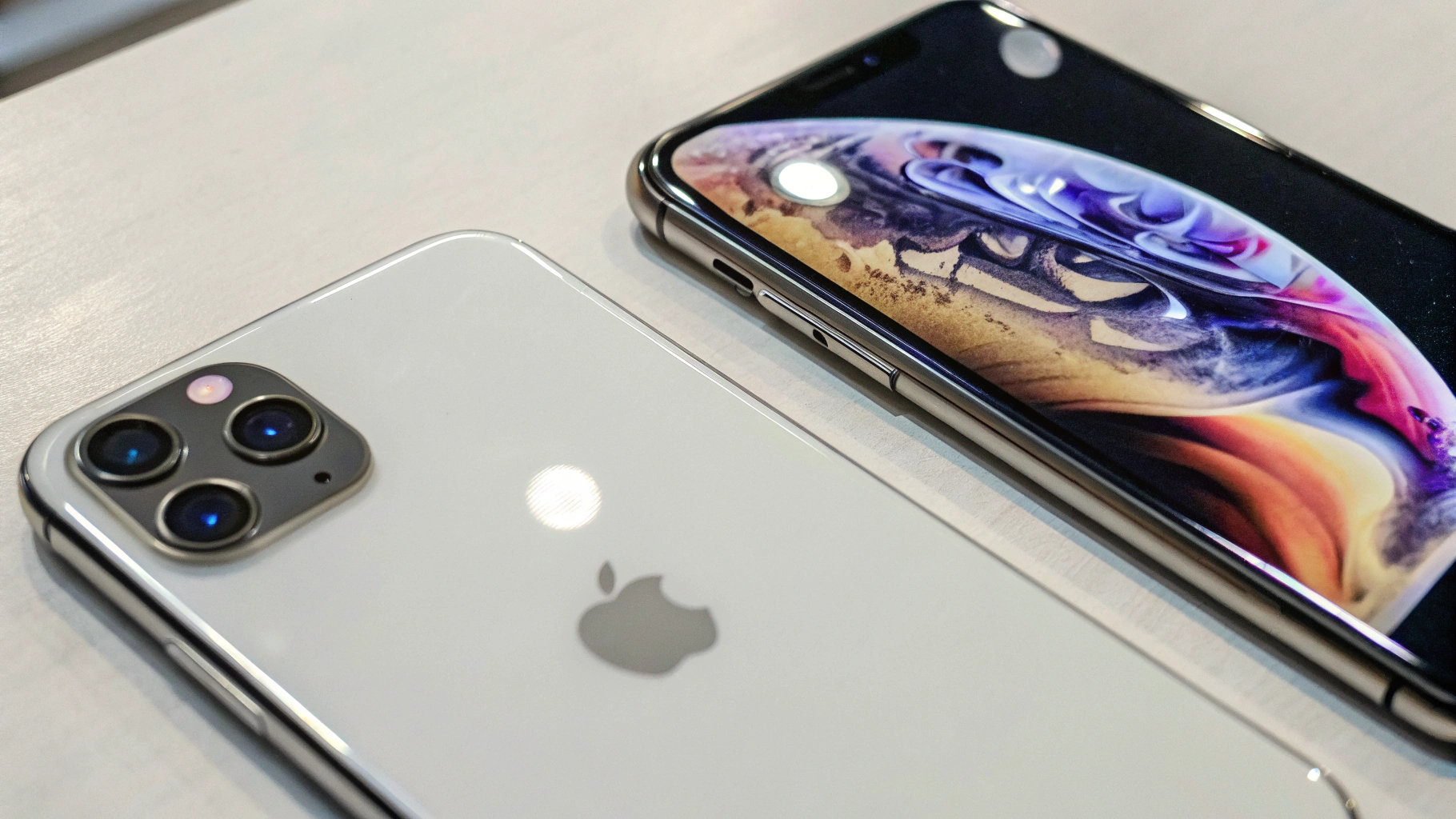 Два iPhone на столе, текущая модель и концепт будущего iPhone 18 с акцентом на блок камер и экран