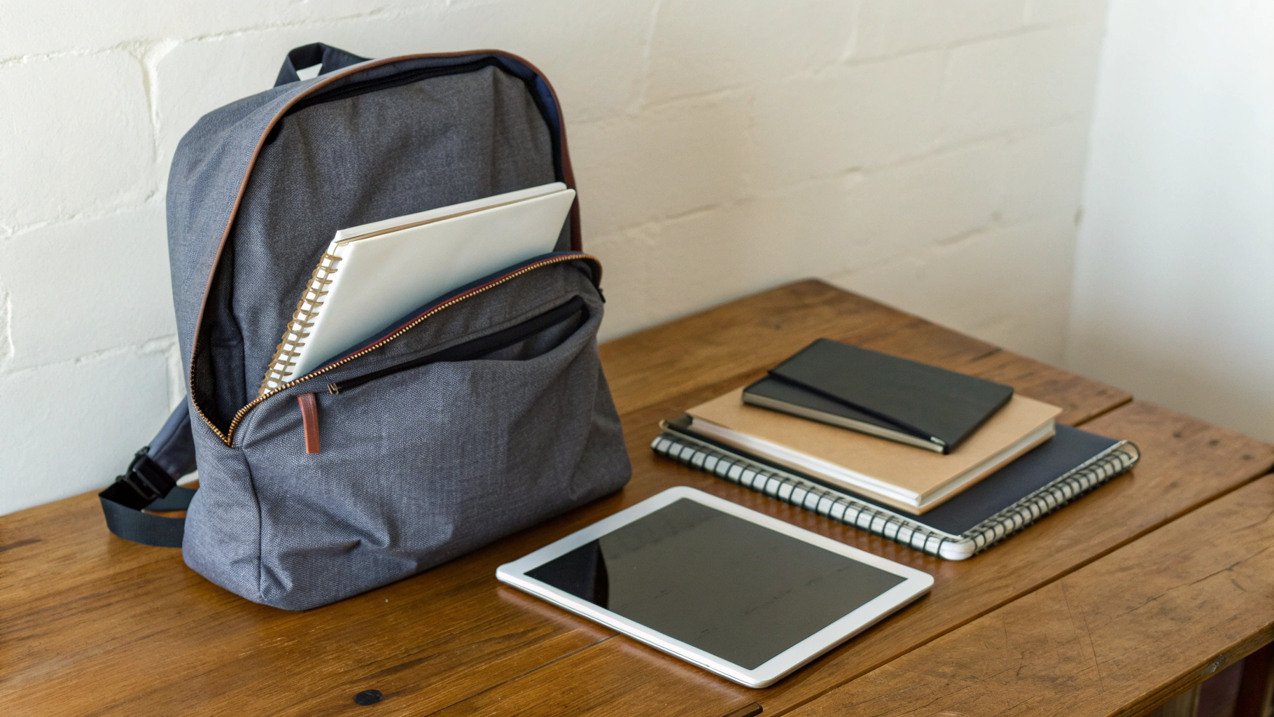 Школьный рюкзак на столе, рядом лежат планшет в защитном чехле и тетради