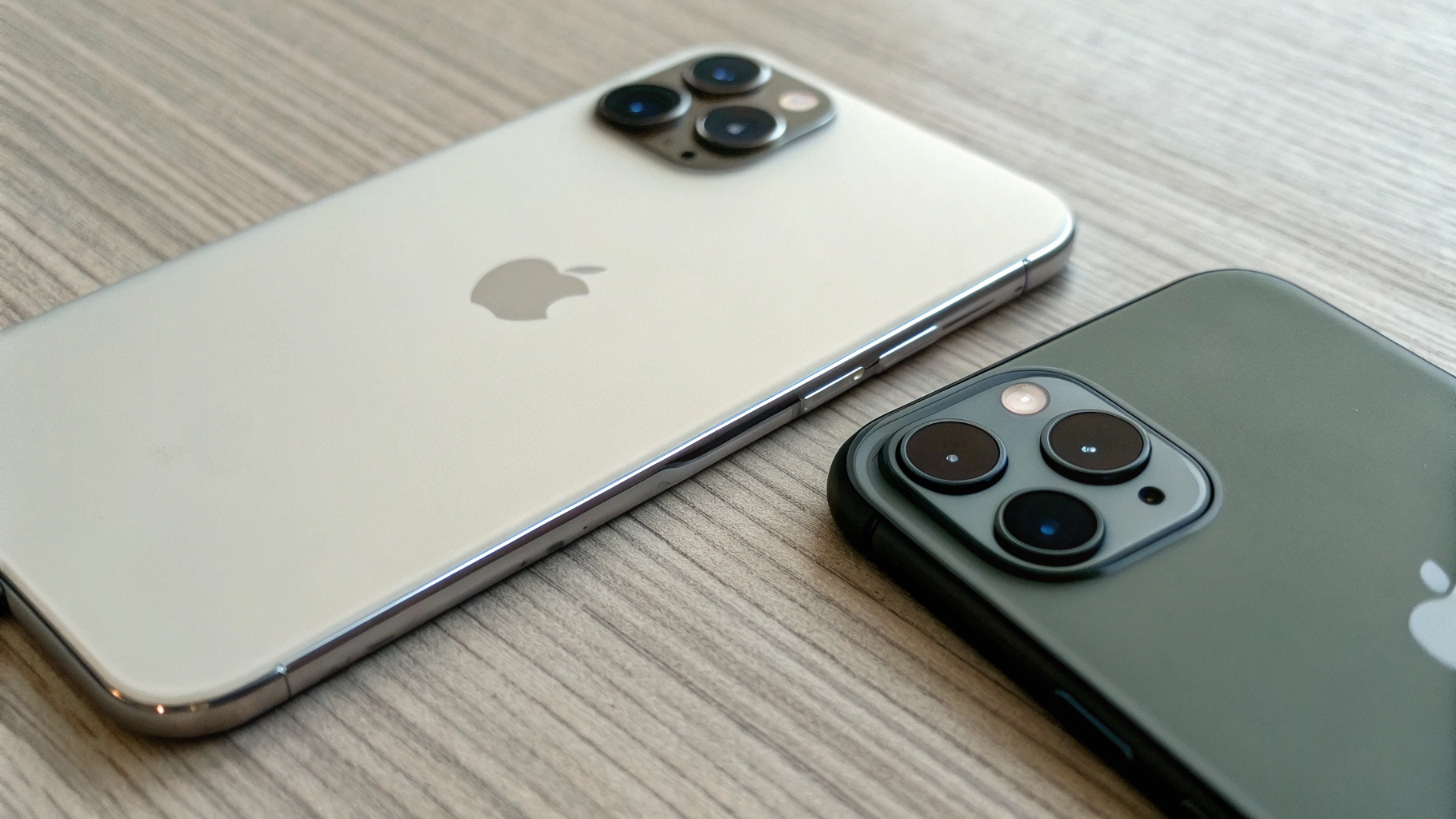 Два iPhone на столе, модель с одной камерой и модель с тройным модулем