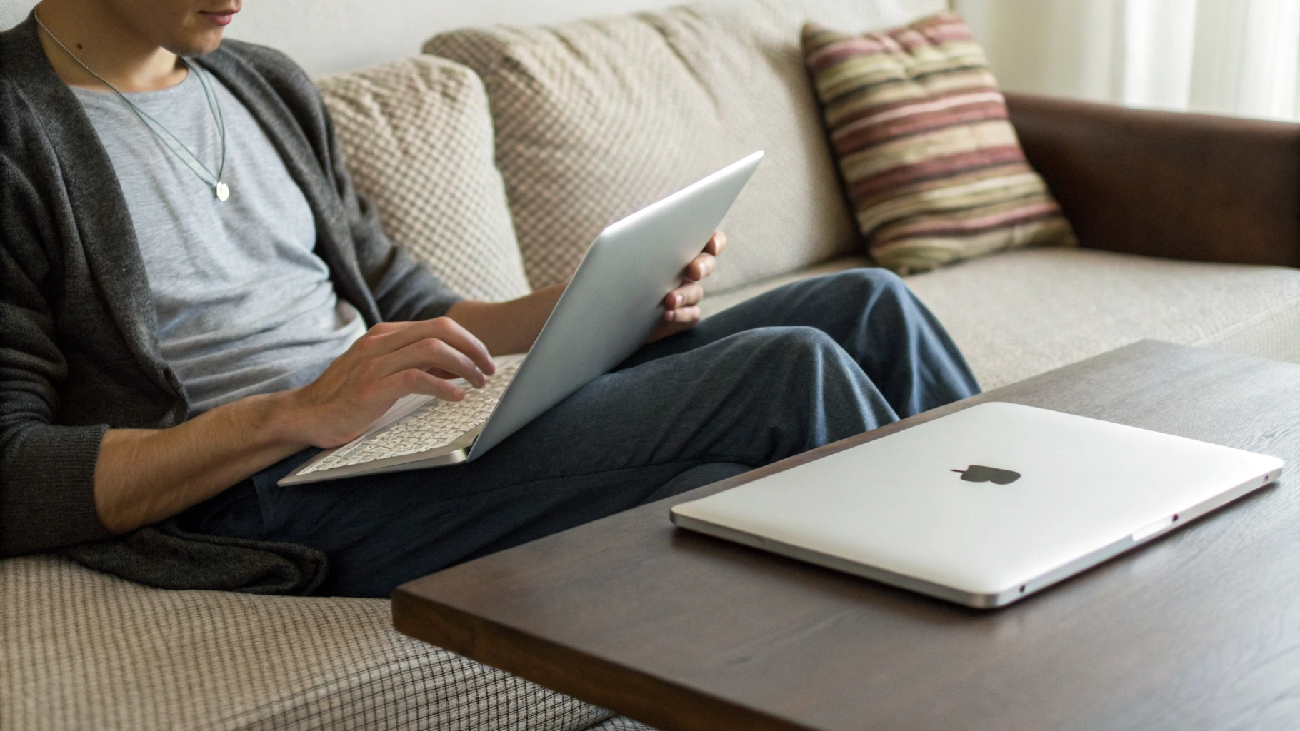 Работа с iPad на диване и закрытый MacBook на столике рядом