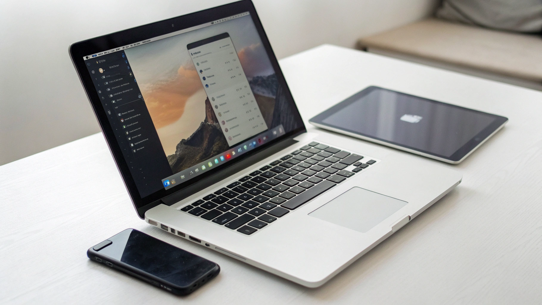 Открытый MacBook с настройками системы и статистикой батареи рядом со смартфоном и планшетом