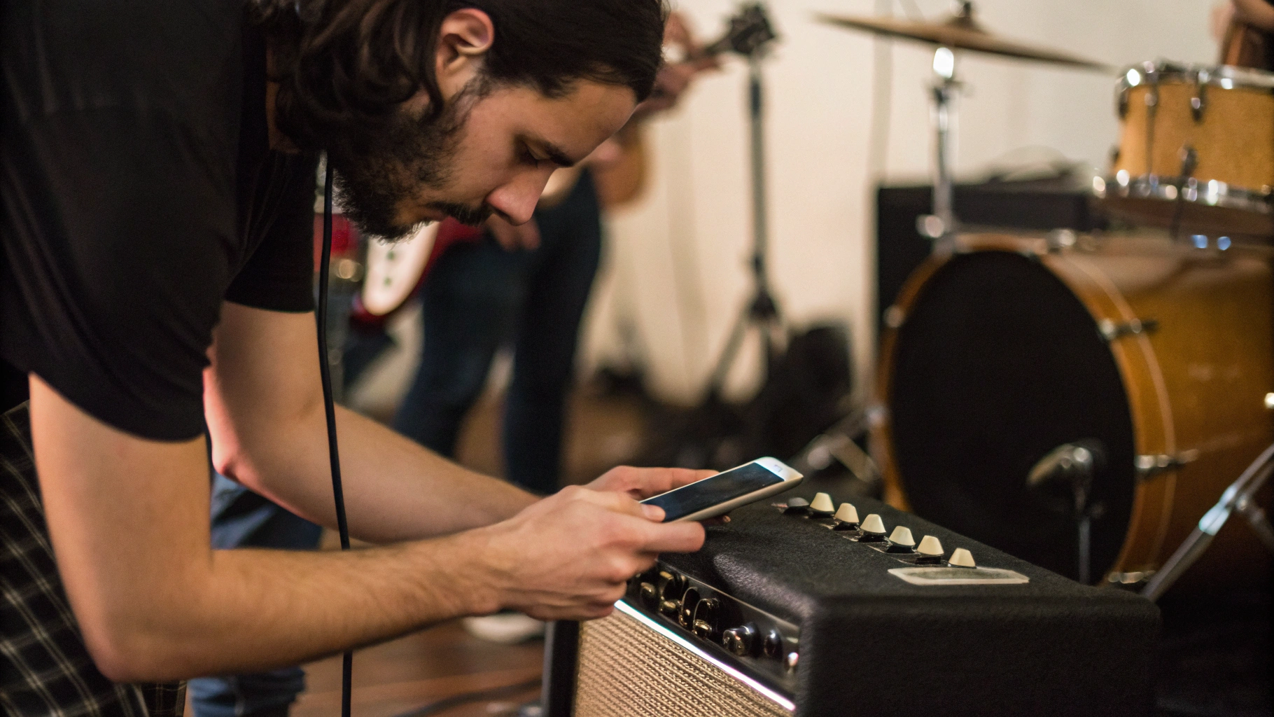 Музыкант ставит смартфон на комбоусилитель, чтобы записать репетицию группы