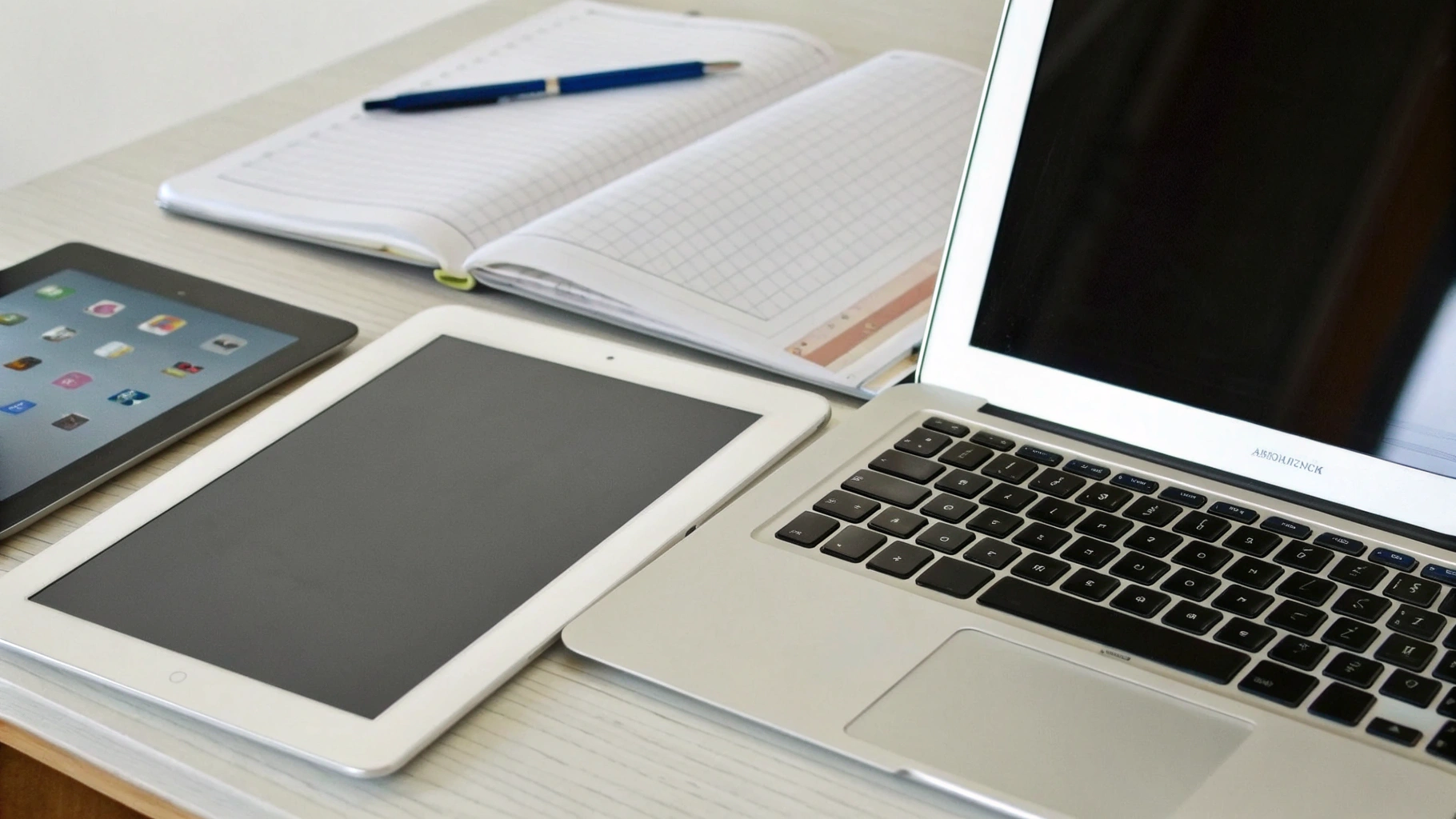 На столе лежат iPad, планшет Samsung Galaxy Tab и недорогой ноутбук рядом с учебниками и тетрадями