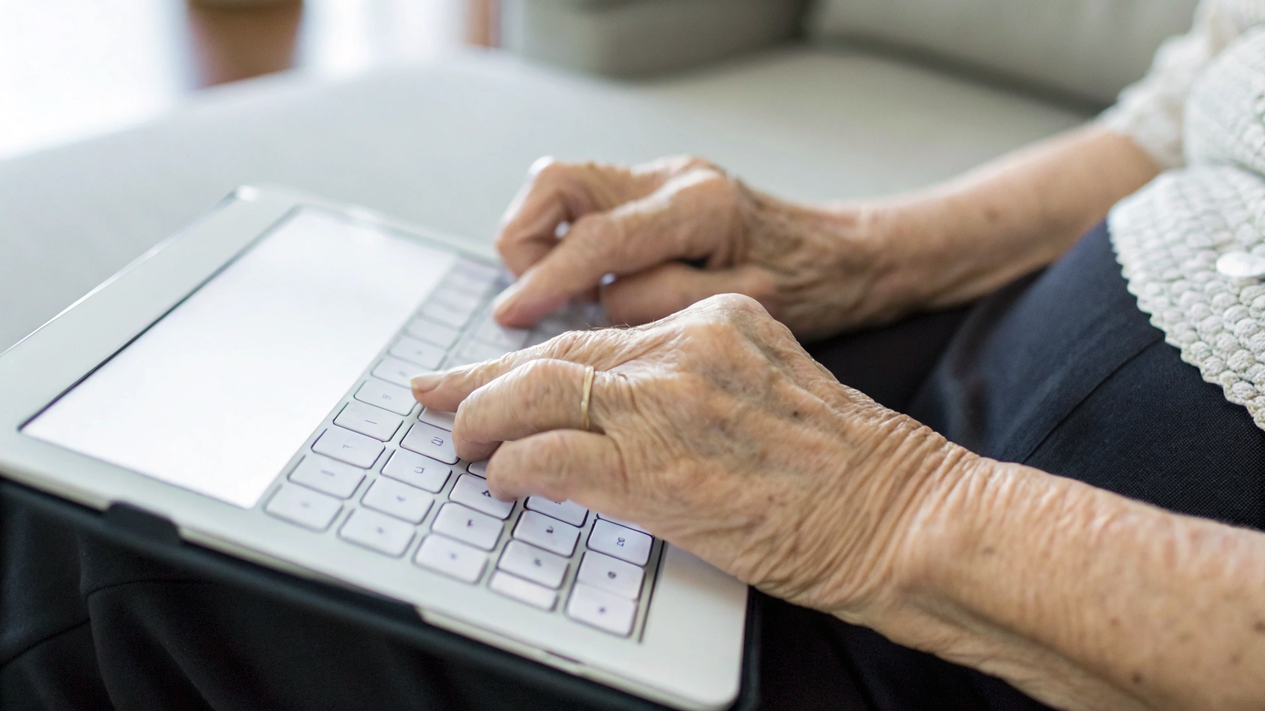 Руки пожилого человека набирают сообщение на крупной экранной клавиатуре планшета