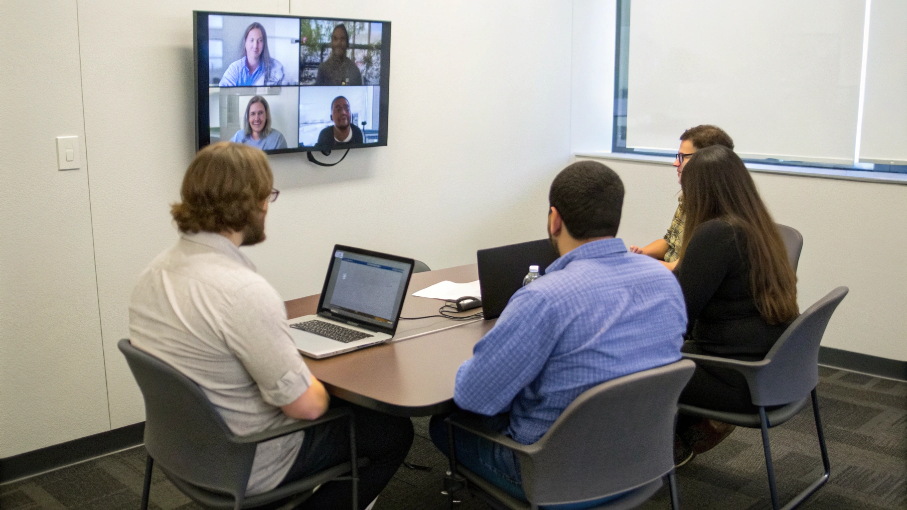 Команда на видеоконференции с недорогим ноутбуком, подключённым к монитору