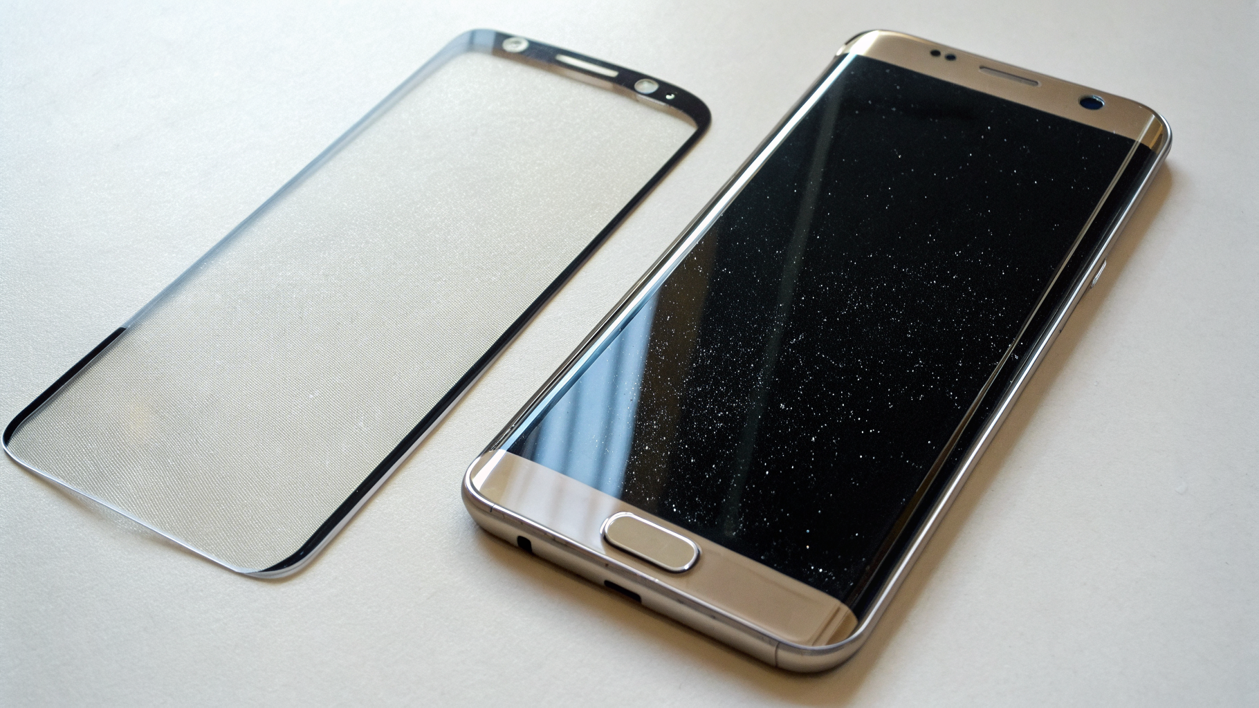 Сравнение защитного стекла и плёнки рядом со смартфоном Samsung Galaxy